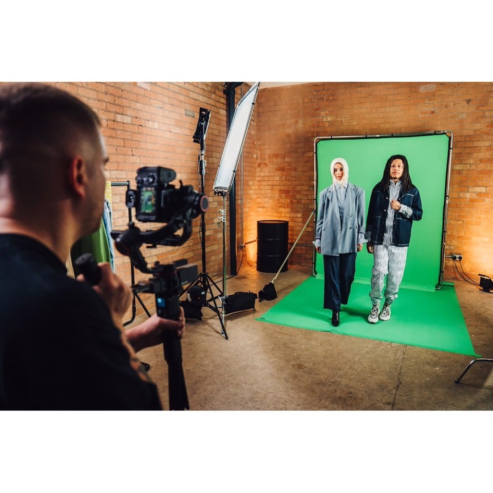 Manfrotto small chroma key green screen in use with two influencers being filmed by one camera person, using a gimbal in a video studio.